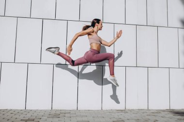 Beyaz tenli, spor yapan, spor yapan, spor yapan, şehirde yoga yapan genç bir kadının yan görüntüsü..