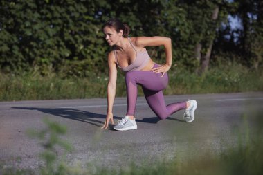 Açık yolda spor yapan zayıf, beyaz tenli genç bir kadının görüntüsü..
