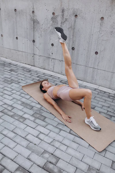 Una giovane donna caucasica sportiva sottile che si allena, fa fitness, yoga sulla strada della città. — Foto Stock