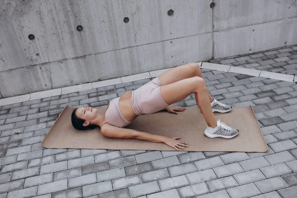 Une jeune femme caucasienne sportive mince s'entraîne, fait du fitness, yoga dans la rue de la ville. — Photo