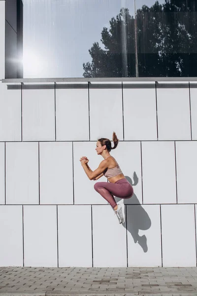 Widok z boku obraz młody szczupły sportowy kaukaski kobieta ćwiczy, robi fitness, joga na ulicy miasta. — Zdjęcie stockowe