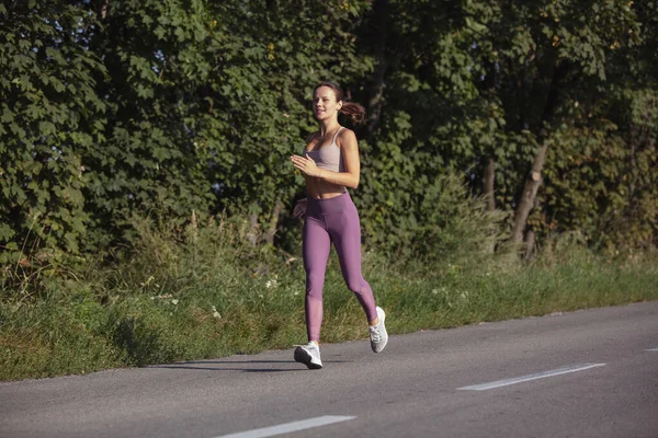 Eine junge schlanke, sportliche Kaukasierin läuft, macht Fitness auf offener Straße. — Stockfoto