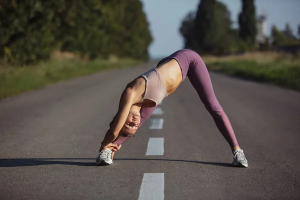 Genç, zayıf, sportif, beyaz bir kadın açık yolda spor yapıyor.. — Stok fotoğraf
