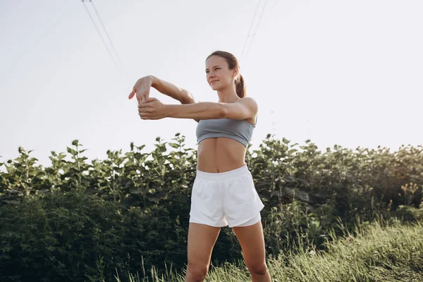 Młoda szczupła sportowa biała kobieta ćwiczy, ćwiczy fitness, joga na świeżym powietrzu na polu słonecznika — Zdjęcie stockowe