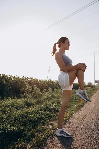 Yan görüş. Genç, zayıf, sportif, beyaz kadın görüntüsü. Ayçiçeği tarlasında spor yapıyor.. — Stok fotoğraf