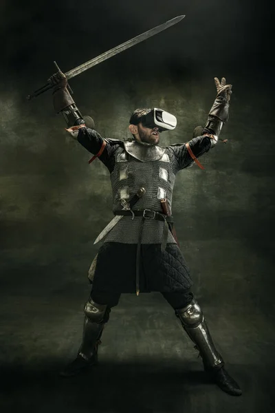 Портрет одного жорстокого бородатого чоловіка, воїна або лицаря в окулярах VR з мечем на темному тлі . — стокове фото