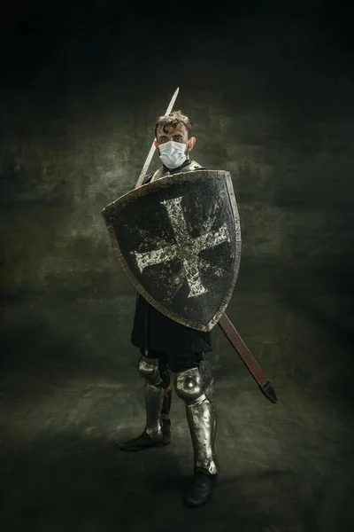 Un hombre barbudo brutal, guerrero medeival o caballero con máscara médica con escudo sobre fondo oscuro. — Foto de Stock