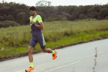 Genç profesyonel erkek triatlet, açık yolda koşuyor. Spor anlayışı, yaşam tarzı, aktivite