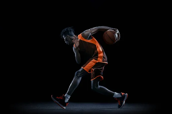 Giocatore di basket africano professionista che pratica con palla isolata su sfondo scuro dello studio. — Foto Stock