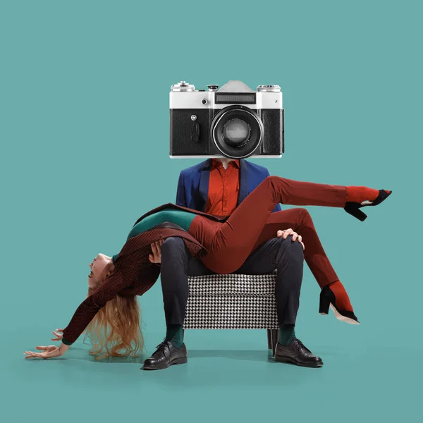 Ung flexibel kvinna ligger i armarna på en man med disco retro-stil kamera i stället för huvudet sitter i fåtölj över blå-grön bakgrund — Stockfoto