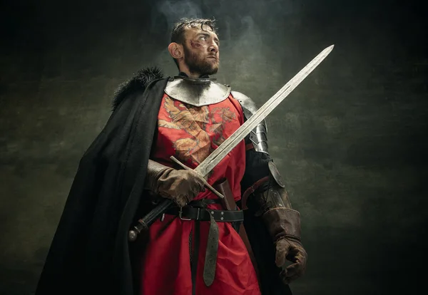 Ein brutaler bärtiger Mann, Medaillenkrieger oder Ritter mit schmutzigem, verwundetem Gesicht und Schwert. — Stockfoto