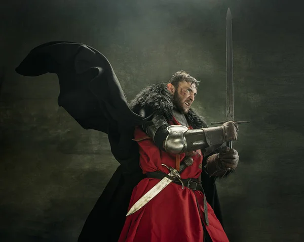 Un hombre barbudo brutal, guerrero medeival o caballero con sucia cara herida sosteniendo espada. — Foto de Stock
