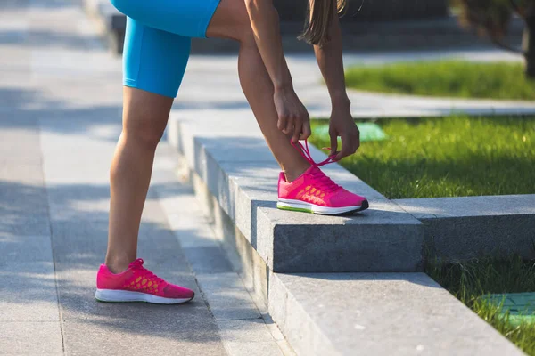 Nahaufnahme von muskulösen weiblichen Beinen in leuchtend rosa Turnschuhen. — Stockfoto