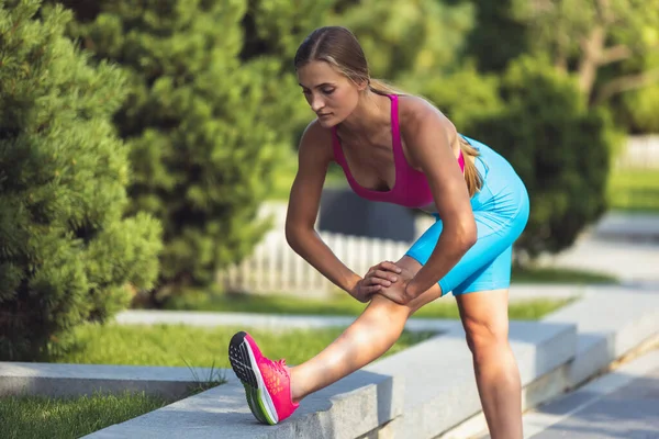 Young slim sportive caucasian woman working out, doing fitness, yoga in the park or on city street. — Stock Photo, Image