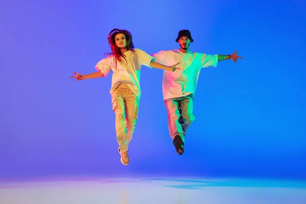 二人の若い人たち,男と女の子でカジュアル服ダンス現代舞踊,ヒップホップ上の青の背景にネオン光. — ストック写真