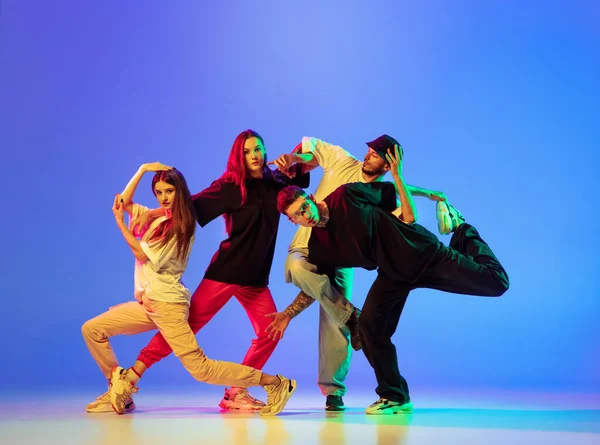 Groupe de jeunes gens, les gars et les filles en danse danse contemporaine, hip-hop, freinage sur fond bleu sous la lumière du néon. — Photo