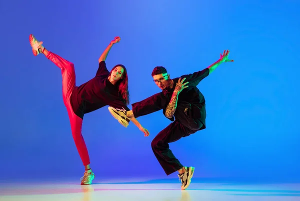 二人の若者、男と女のダンスブレーキ、ネオンの光の中で青の背景にヒップホップ. — ストック写真