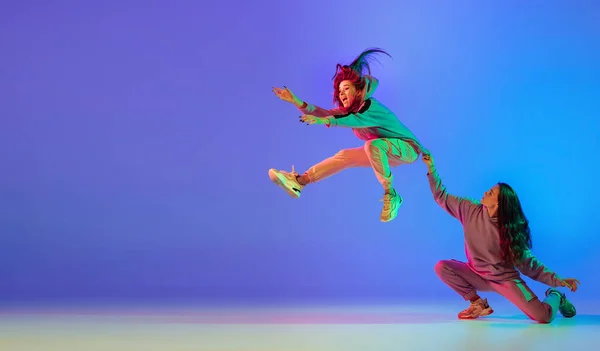 Danza contemporánea. Dos jóvenes hermosas mujeres bailando frenado, hip-hop sobre fondo azul en luz de neón. — Foto de Stock