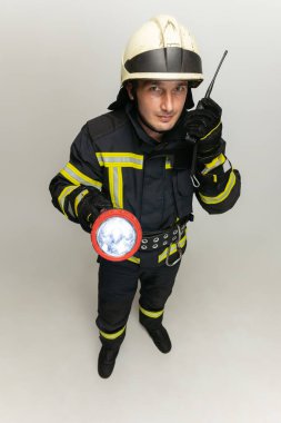 Üniformalı bir erkek itfaiyeci beyaz stüdyo arkasında poz veriyor..