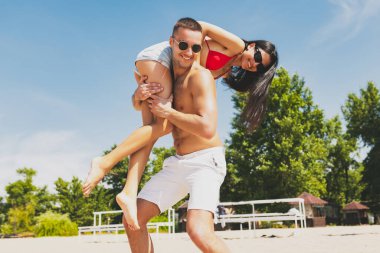 Gençler, erkekler ve kadınlar plajda dinleniyor, eğleniyor, güneşleniyor.