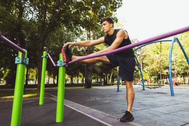 Genç, yakışıklı, beyaz bir adam spor giyimi eğitimi alıyor. Açık bir yaz gününde yaya geçidinde egzersiz yapıyor..