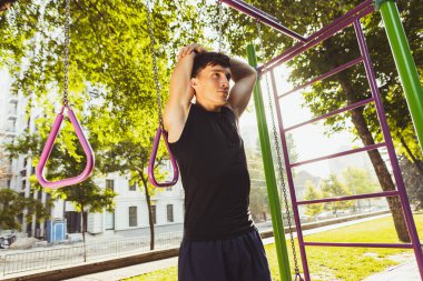 Genç, yakışıklı, beyaz bir adam spor giyimi eğitimi alıyor. Açık bir yaz gününde yaya geçidinde egzersiz yapıyor..