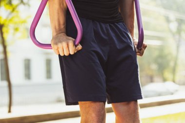 Spor giyimli yakışıklı beyaz bir adam parlak bir yaz gününde spor sahasında yaya koşusu yapıyor. Kesilen resim