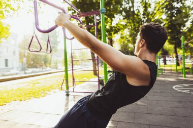 Spor kıyafetli yakışıklı beyaz bir adam parlak bir yaz gününde spor sahasında yaya geçidinde koşuyor..