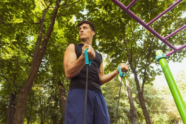 Beyaz giyimli yakışıklı bir adam parlak bir yaz gününde yaya geçidinde iple atlıyor..