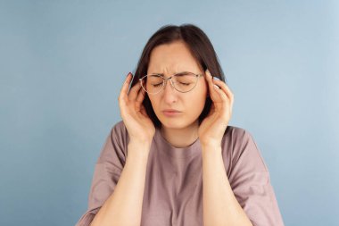 Yakın plan. Mavi stüdyo arka planında izole edilmiş genç beyaz kadın portresi.