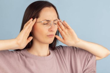 Yakın plan. Mavi stüdyo arka planında izole edilmiş genç beyaz kadın portresi.