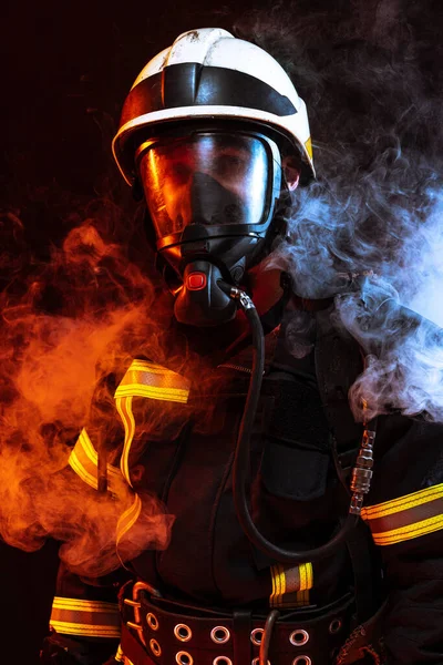 Jeden umundurowany strażak pozujący na czarne tło pokryte dymem — Zdjęcie stockowe