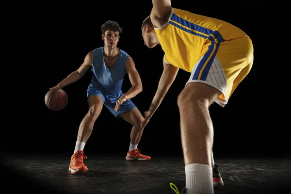 Competitieve sport. Twee mannelijke atleten, professionele basketbalspelers in actie, beweging geïsoleerd over zwarte achtergrond. — Stockfoto