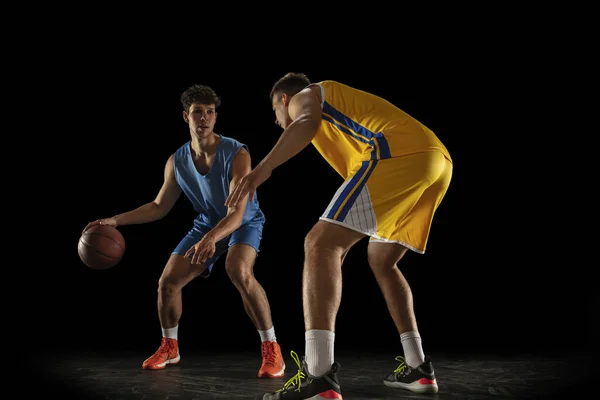 Desporto competitivo. Dois atletas do sexo masculino, jogadores profissionais de basquete em ação, movimento isolado sobre fundo preto. — Fotografia de Stock