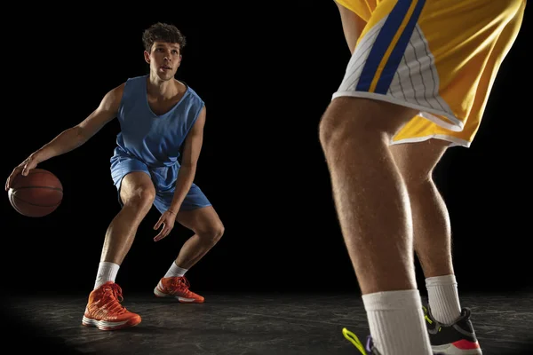 Konkurrenskraftig sport. Två manliga idrottare, professionella basketspelare i aktion, rörelse isolerad över svart bakgrund. — Stockfoto
