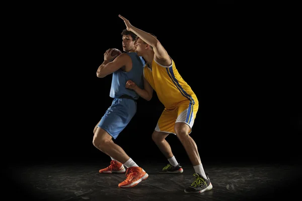 Leistungssport. Zwei männliche Athleten, Basketballprofis in Aktion, Bewegung isoliert über schwarzem Hintergrund. — Stockfoto