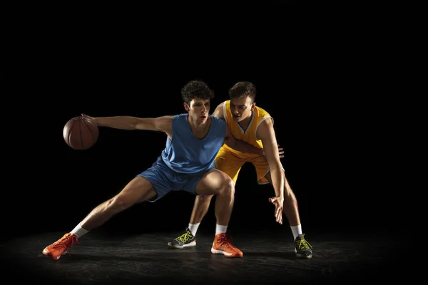 Konkurrenskraftig sport. Två manliga idrottare, professionella basketspelare i aktion, rörelse isolerad över svart bakgrund. — Stockfoto