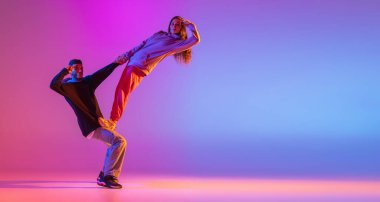 El ilanı. İki genç insan, erkek ve kız çağdaş dans ediyorlar, pembe arka planda pembe ışıkta hip-hop yapıyorlar..