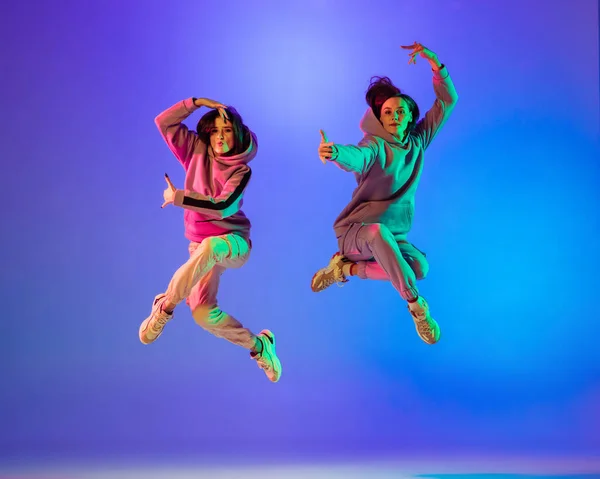 二人の若いです女の子でカジュアル服ダンス現代舞踊,ヒップホップ上の青の背景にネオンライト. — ストック写真