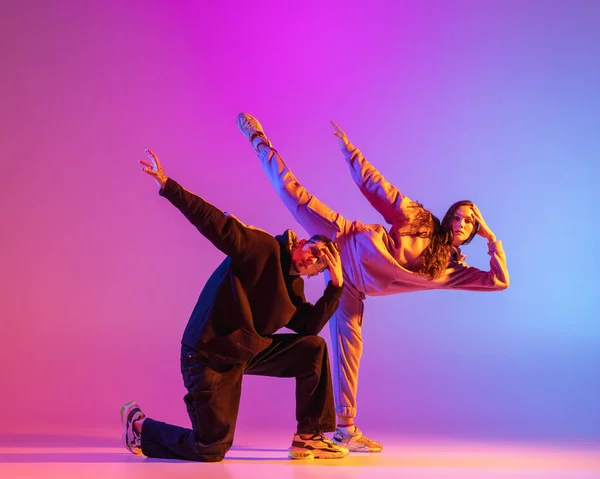 二人の若い人たち,男と女の子でカジュアル服ダンス現代舞踊,ヒップホップピンクの背景にネオンライト. — ストック写真
