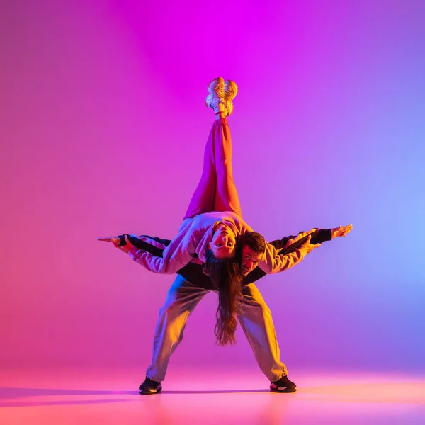 二人の若い人たち,男と女の子でカジュアル服ダンス現代舞踊,ヒップホップピンクの背景にネオンライト. — ストック写真