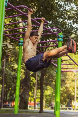 Spor giyim antrenmanında genç, yakışıklı beyaz bir adam açık havada spor yapıyor..