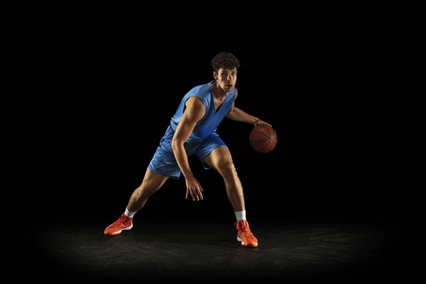 En ung kaukasiska professionell basketspelare tränar med bollen isolerad på svart bakgrund — Stockfoto
