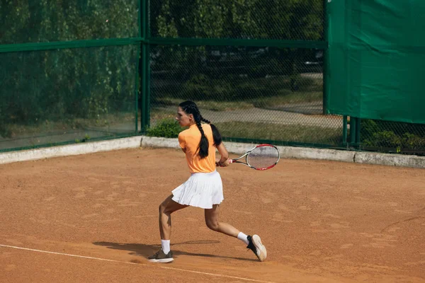 Belle jeune sportive, joueuse de tennis professionnelle avec raquette pratiquant sur un court de tennis en terre battue en journée d'été. — Photo