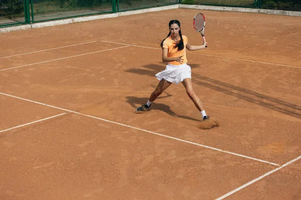 Gyönyörű fiatal sportoló, profi teniszező ütő gyakorló salak teniszpálya nyári napon. — Stock Fotó