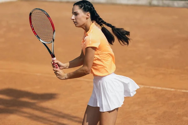 Vacker ung idrottskvinna, professionell tennisspelare med racket tränar på lera tennisbana i sommar dag. — Stockfoto