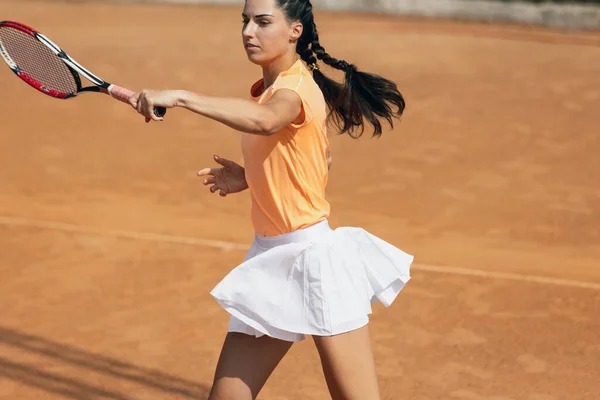 Jedna krásná mladá sportovkyně, profesionální tenistka s raketou cvičící na hliněném tenisovém kurtu v letní den. — Stock fotografie