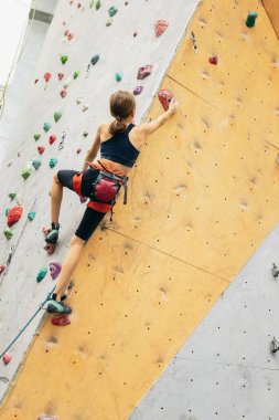 Tırmanma merkezinde taş duvarda pratik yapan tatlı bir genç kız. Sportif yaşam tarzı, aktivite, mutlu çocukluk kavramı