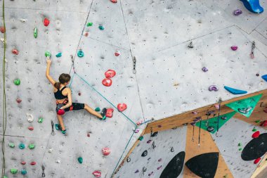 Tırmanma merkezinde taş duvarda pratik yapan tatlı bir genç kız. Sportif yaşam tarzı, aktivite, mutlu çocukluk kavramı