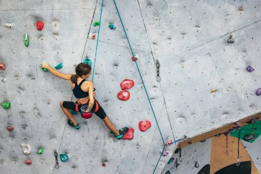 Tırmanma merkezinde taş duvarda pratik yapan tatlı bir genç kız. Sportif yaşam tarzı, aktivite, mutlu çocukluk kavramı
